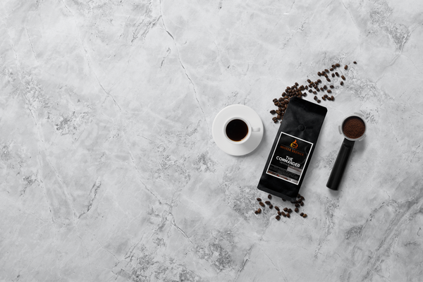 An aerial photo of a bag of coffee beans, a cup of delicious coffee, whole beans, and ground beans in an espresso portafilter.
