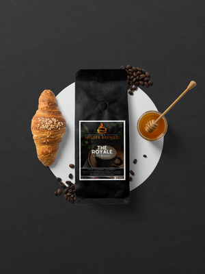 An aerial photo of a bag of The Royale roast alongside an almond croissant and a pot of honey.