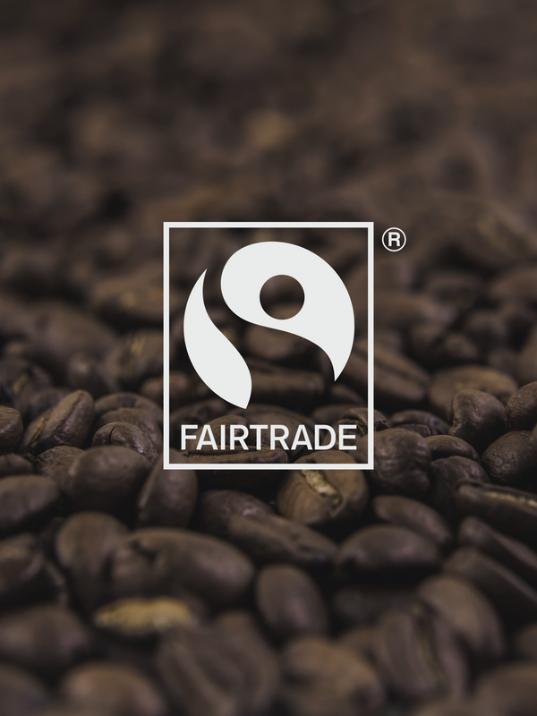 Certified Fair Trade logo overlaid on top of a photo of our high quality roasted beans, roasted in Canada